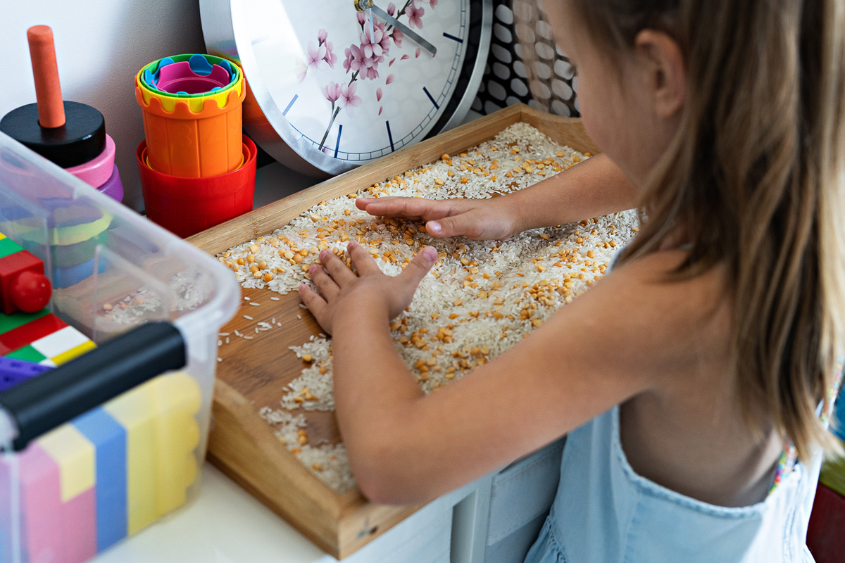 Dziewczynka miesza na tacy ryż z grochem
