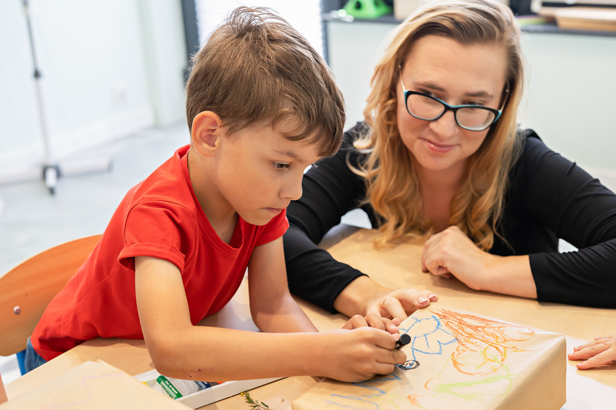chłopiec i kobieta, chłopiec rysuje na pudełku